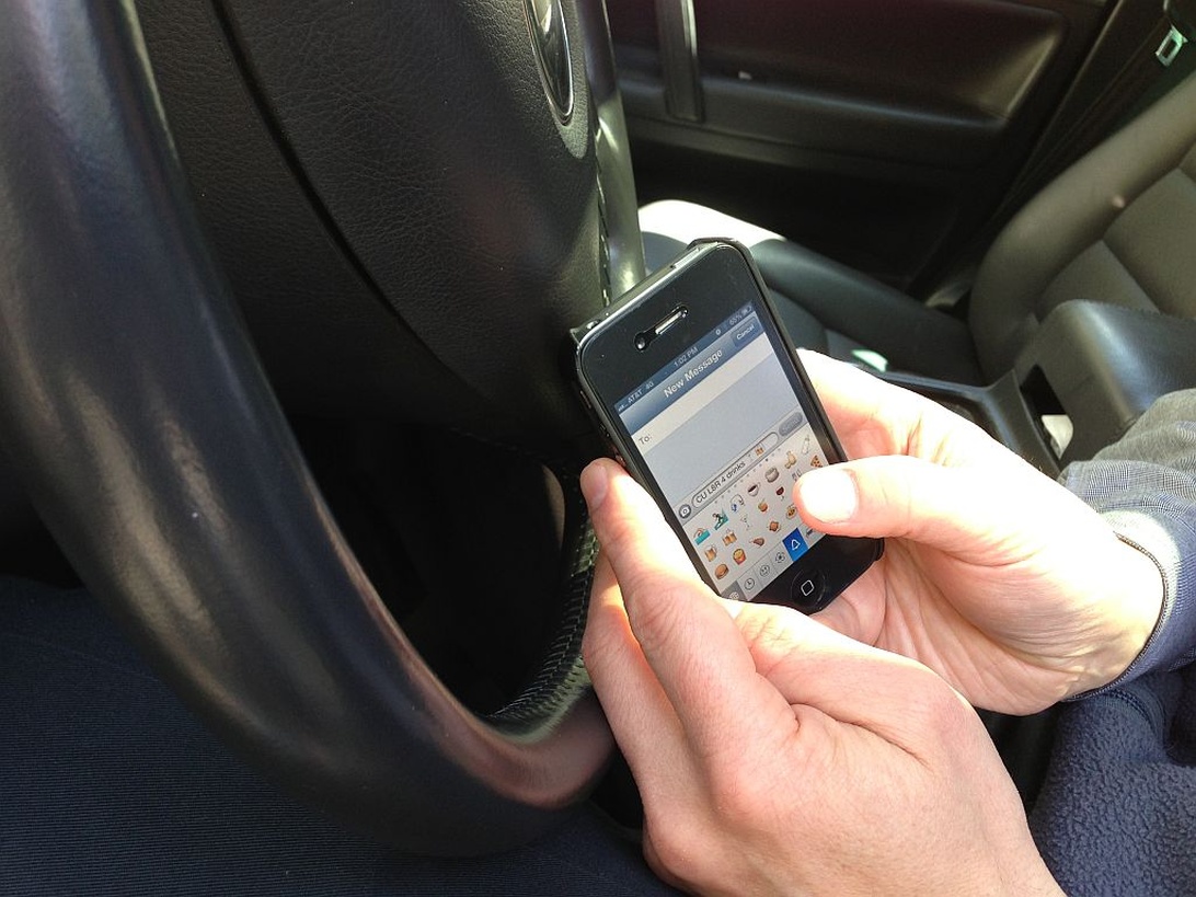 En person som använder en smartphone med en bil-app för att aktivera en ny funktion i sin bil.